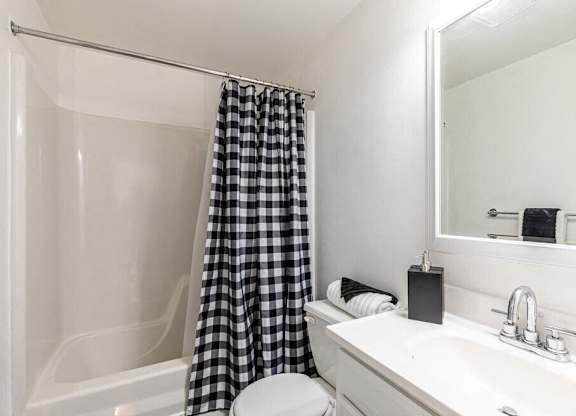 A white bathroom with a black and white checkered shower curtain.