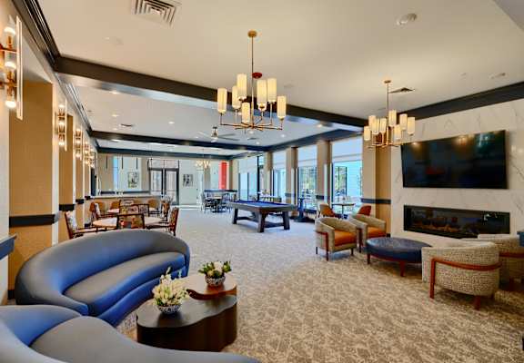 A large, well-lit room with a variety of seating options and a fireplace.