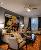 A family of four is sitting on a couch in a living room.