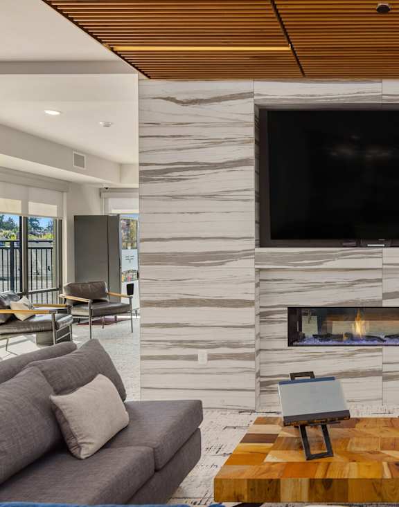 A modern living room with a stone fireplace and a flat screen TV mounted above it.
