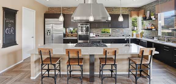 A modern kitchen with a large island and wooden chairs.