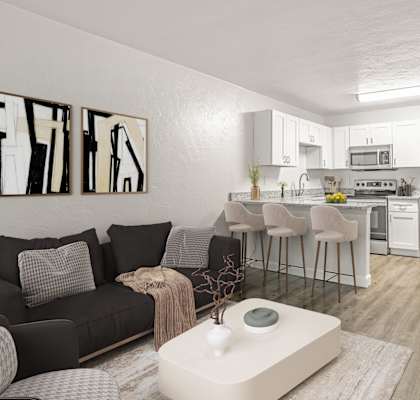 a living room with a kitchen in the background and a large white coffee table in the foreground