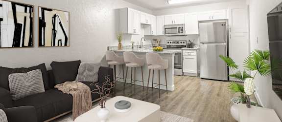 a living room with a kitchen in the background and a large white coffee table in the foreground