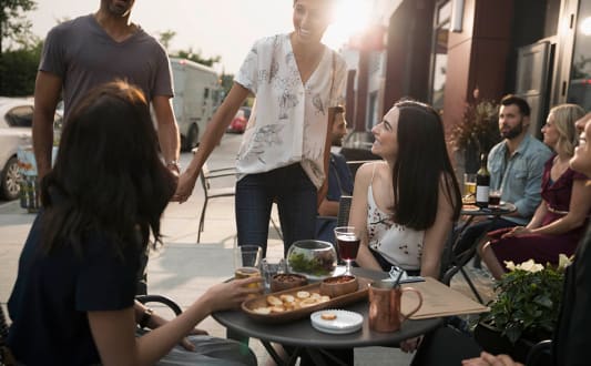 a group of people sitting at a patio table with food