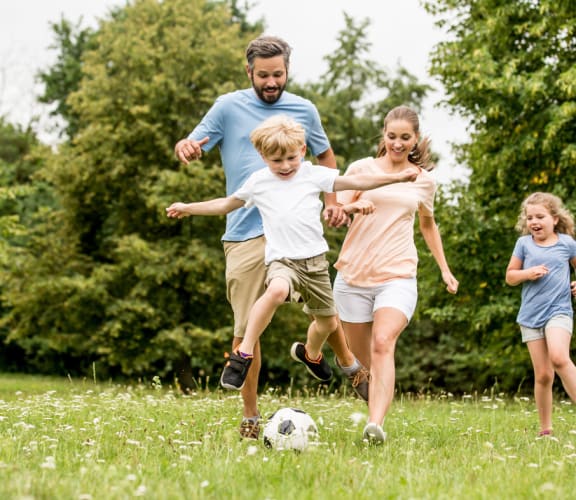 a family playing soccer in a park