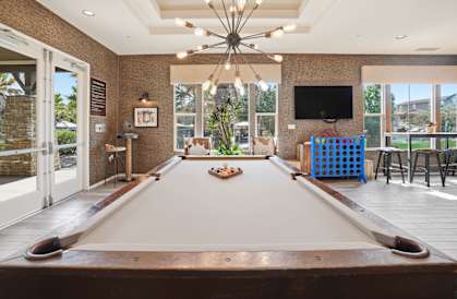 A pool table in a room with a television and a bar.