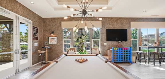 A pool table in a room with a television and a bar.