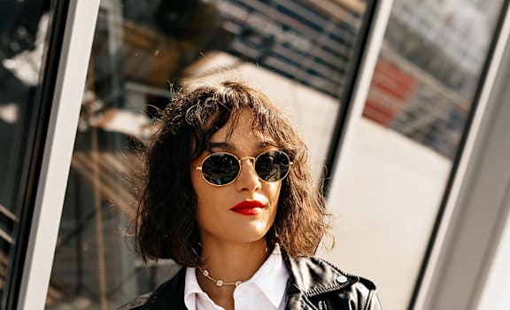 A woman in a black leather jacket is looking at her phone.