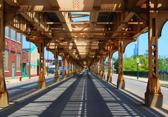 A long, empty road under a bridge with metal supports.