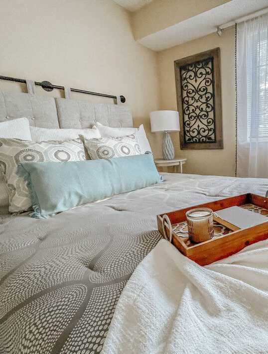 A tray with a candle and a glass sits on a bed.