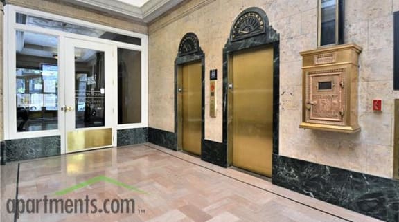 a lobby with two elevators and a grandfather clock