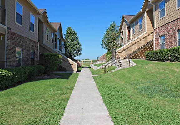 A long concrete walkway separates two rows of apartment buildings.