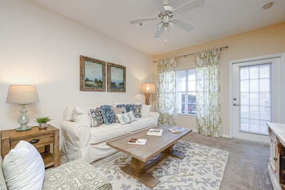 A living room with a white couch, a wooden coffee table, and a ceiling fan.