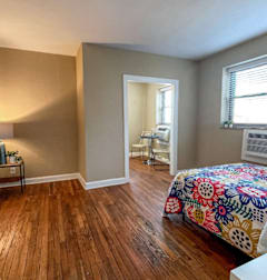 A bedroom with a bed, chair, and window.at Convent Gardens Apartments, St. Louis, MO