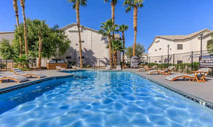 A swimming pool surrounded by palm trees and lounge chairs.