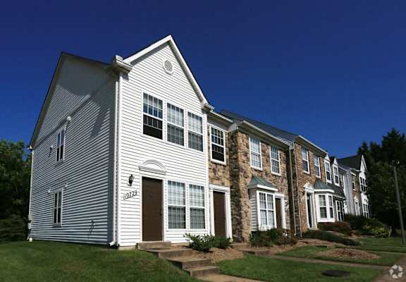 a white house with a stone facade and a blue sky