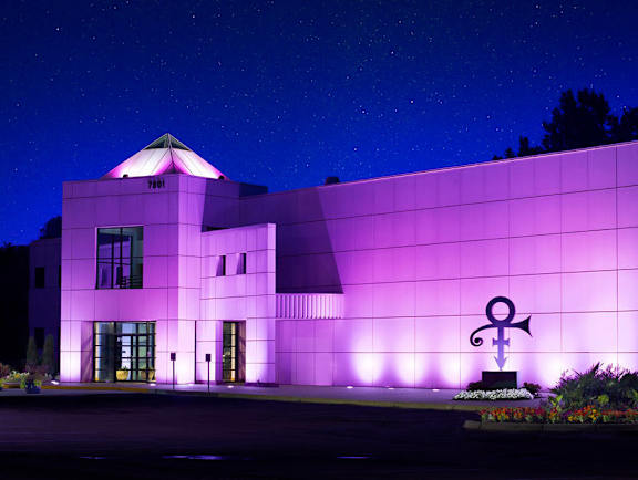 A building with a purple light on it and a statue in front of it.