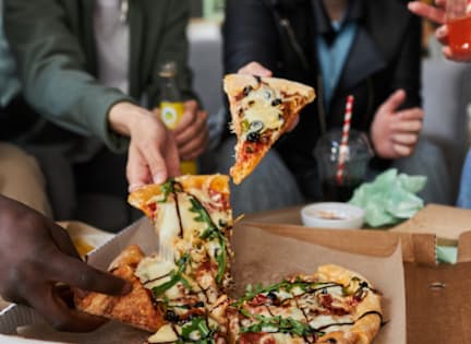 A slice of pizza is being lifted from a box.
