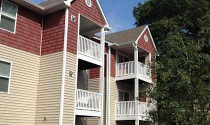 A red and beige apartment building with a black fence in front.