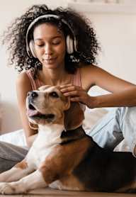 A woman with headphones is petting a dog.