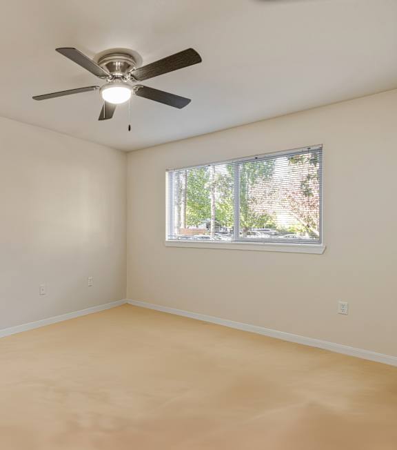 Empty room with a ceiling fan and a window.
