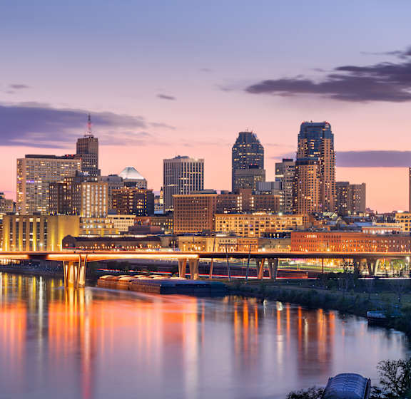 A city skyline at dusk with a river running through it.