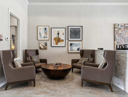 a living room with brown chairs and a table