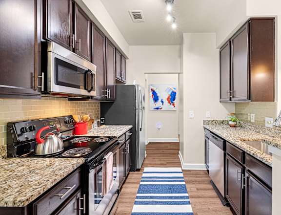 A kitchen with dark brown cabinets and granite countertops.
