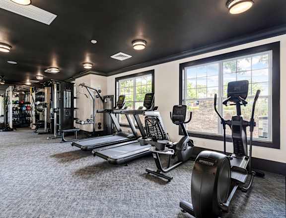 A gym with a variety of equipment including treadmills, weights, and exercise machines.