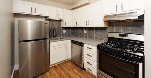 A kitchen with a stainless steel refrigerator, oven, and wooden floors at Retro 511 Apartments, West Haven, 06516