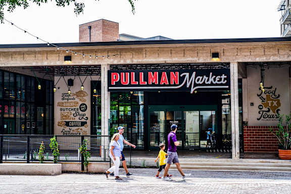 A woman and a child are walking past a Pullman Market.