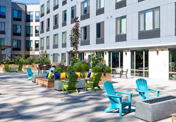 a courtyard with blue chairs and tables in front of a building
