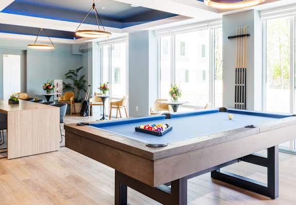 a pool table in a living room with windows