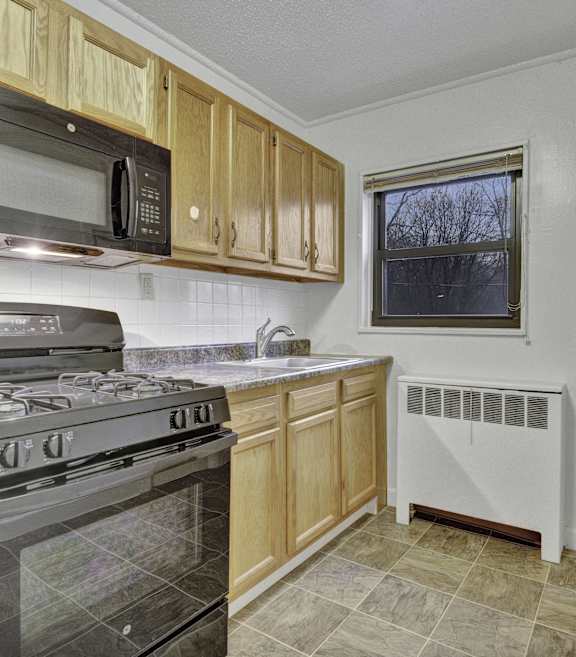 A kitchen with a stove, oven, microwave, and a window.
