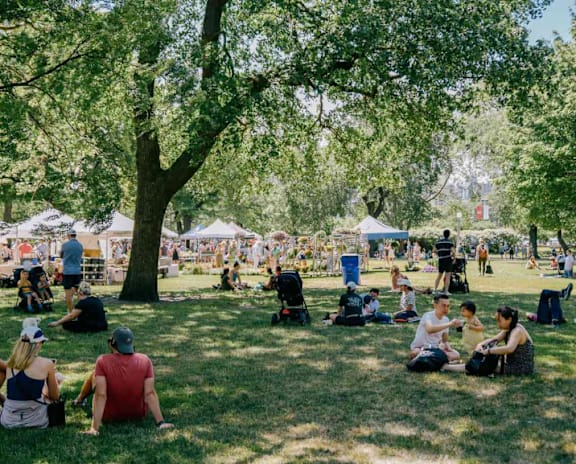 A group of people are sitting on the grass in a park.
