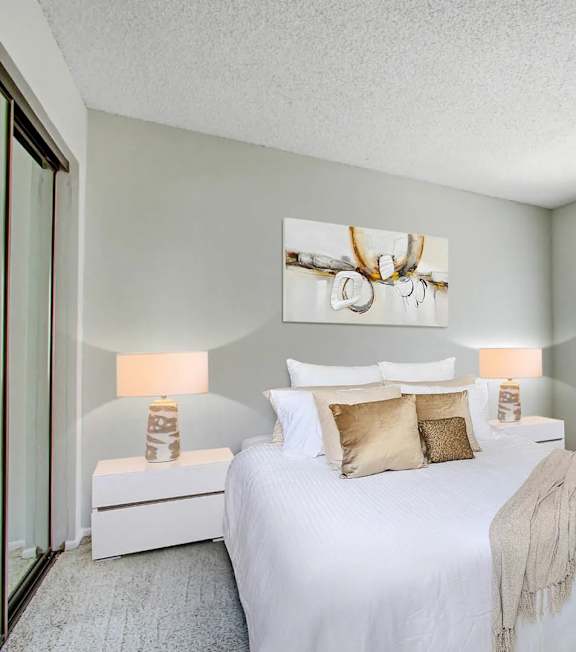 A bedroom with a large bed and a painting above it.