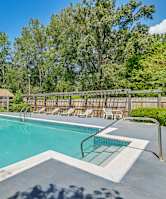 A swimming pool in a backyard with a house and trees in the background.