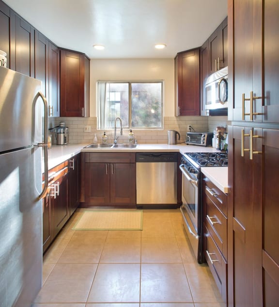 A kitchen with wooden cabinets and a stainless steel refrigerator.