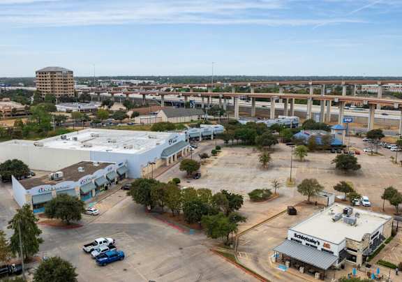 A parking lot with a building and a bridge in the background.