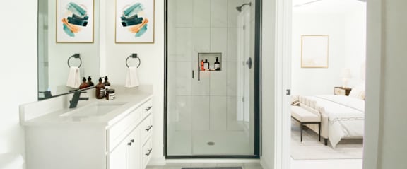 A white bathroom with a glass shower door and a white sink.