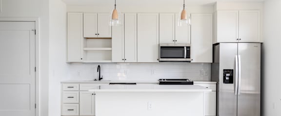 A kitchen with white cabinets and a black countertop.