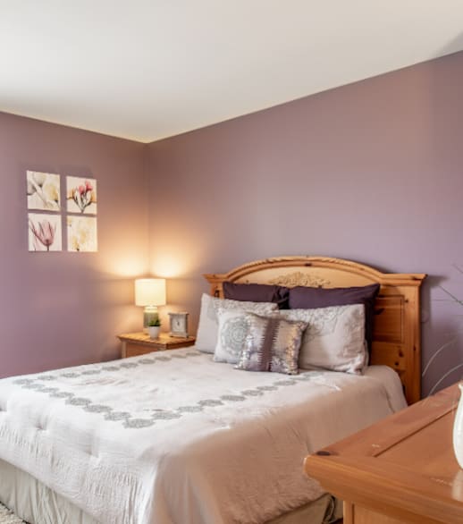 A bedroom with a bed, nightstand, and a window with curtains.