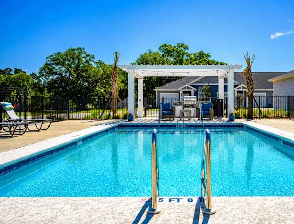 A swimming pool with a diving board and lounge chairs.