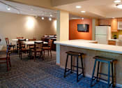 Thumbnail 3 of 14 - Community room with kitchen, bar seating, and square tables