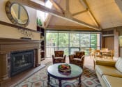 Thumbnail 14 of 25 - Community room with chairs facing fireplace, high ceilings with wooden archways, and large windows