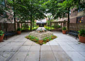 Thumbnail 23 of 25 - Enterance courtroom with stone centerpiece flanked by park benches and plants