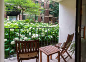 Thumbnail 10 of 25 - Outdoor patio with wooden chairs facing tall fauna