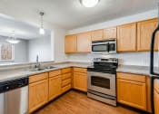 Thumbnail 3 of 22 - kitchen with bright wooden cabinets, gray countertops, and stainless steel black and silver appliances