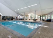Thumbnail 5 of 22 - Indoor pool with high ceiling and patio seating