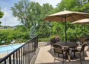 Thumbnail 14 of 23 - Sun deck with circular tables shielded by umbrellas overlooking a pool